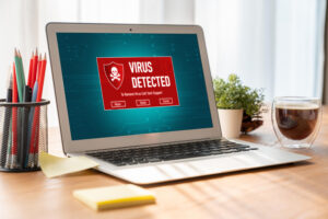 A laptop on a desk displaying the words “Data Protection and Privacy” on the screen, with stationery and a plant beside it.